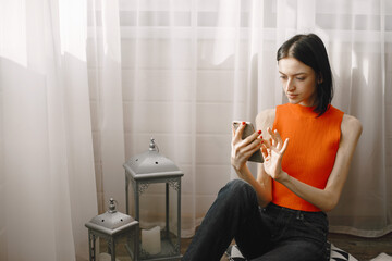 Girl in an orange jacket sits on floor and drinks juice