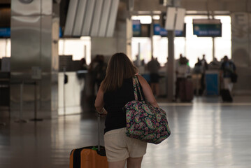 A woman rushes towards a crowded check in counter at an airport