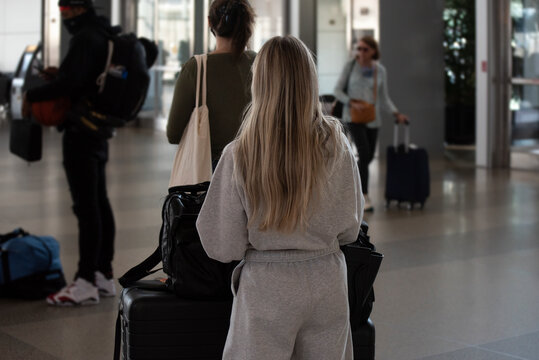 A young, blonde woman stands in line at the airport. 