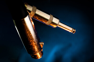 Macro Closeup of Quarter Inch Connector End of Microphone Cable Behind XLR End on Teal Background with Orange Lighting