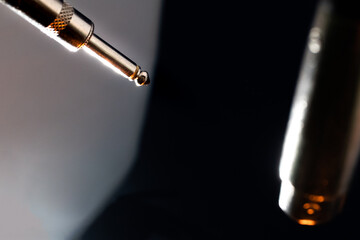 Abstract Closeup of Ends on Microphone Cable with Metal Quarter Inch Connector in Front of White Background and XLR Connector in Front of Black Background