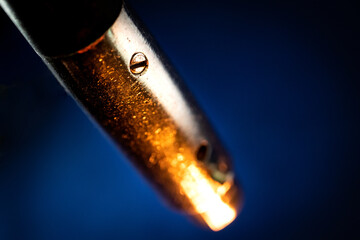 Macro Closeup of Screw on Worn Out and Scratched Male XLR Connector Isolated on Blue Background with Orange Lighting