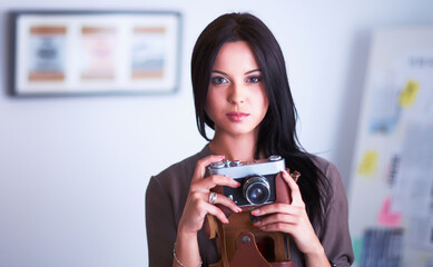Young woman watching footage on film, standing near window