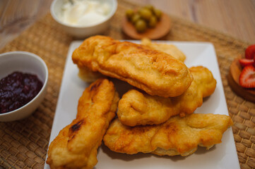 Wooden board with fried zucchini in batter, sauce, jam, and strawberries
