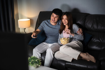 happy couple watching TV on sofa at night
