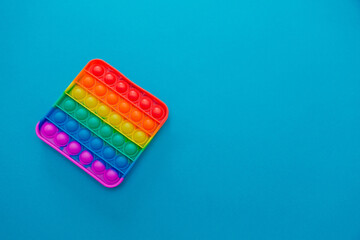 Rainbow sensory fidget isolated on blue background. New trendy silicone toy. Push pop bubble Silicone fidget toys.