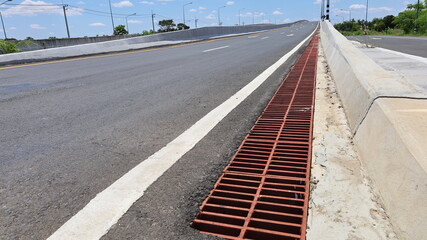 Metal grilles on the side of the road. Bridge ditch for drainage beside the barrier with copy...