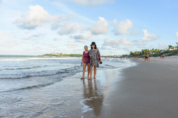 Idosa caminhando na praia com de bem com a vida