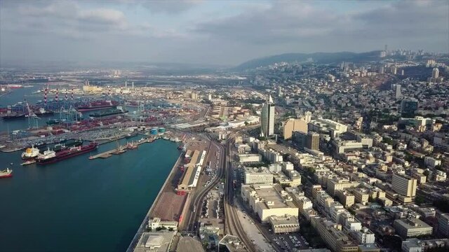 Aerial Forward Shot Of Commercial Dock In City Against Cloudy Sky, Drone Flying Over Street During Day - Haifa, Israel