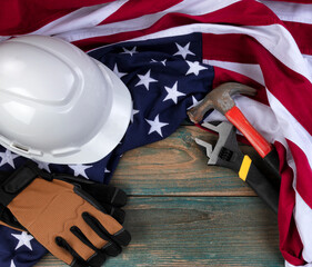 Happy Labor Day background with American flag and construction equipment tools on faded blue wood