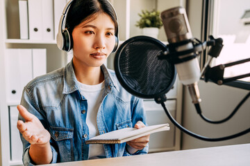 young women recording podcasts with headphones and microphones, female broadcasting live in the...