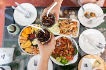 A group of friends beating glasses to celebrate success on the dining table.