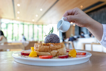 Ice cream on bread topped with honey, decorated with strawberry and orange pulp.