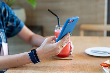 Woman playing mobile phone With watermelon smoothie placed on the side