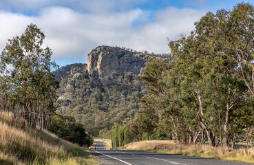 A typical rural Australia scene with road, rocky cliffs & trees - heading south on New England Highway, NSW, Australia