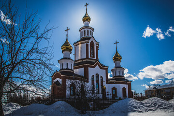 the bright spring sun peeps out from behind the golden domes of the Orthodox church