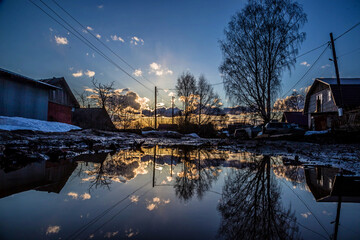 Obraz premium small wooden houses are reflected in a huge puddle on the road
