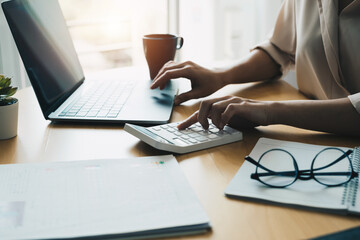 Close up woman using computer calculating finance or taxes on machine, female manage home family expenditures, using calculator, make payment on laptop