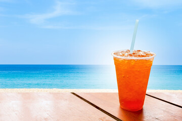 Obraz premium Ice tea in plastic cup over the beach, cold soft drink, summer concept