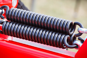 Big and hard black steel spring as part and detail of industrial or agricultural machine