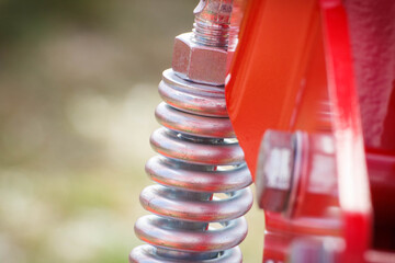 Hard spring made of steel. Part and detail of red industrial or agricultural machine