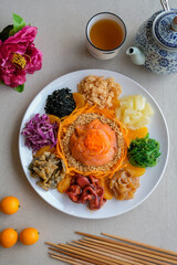 Delicious and colorful display of Chinese prosperity cuisine / Yee Sang aka Prosperity Toss / Carrot strips, purple cabbage, fresh seaweeds, jelly fish, deep fried fish skin, ground peanuts, fritters