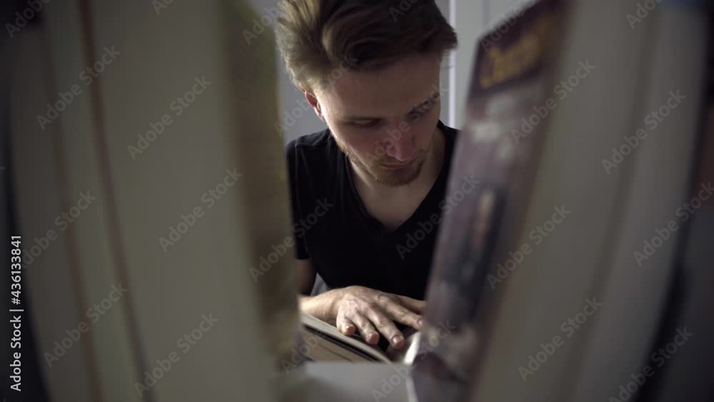 Poster young man reading a book and placing it on a bookshelf.