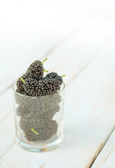 Fresh black mulberry in a jar glass or bowl on the wooden table. Mulberry close-up. Organik freshly harvested berries natural superfood