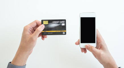 The businessman's hand is holding a credit card and using a smartphone for online shopping and internet payment in the office