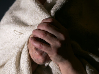 Dirty hands of poor woman wrapped in a blanket
