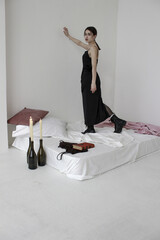 Vertical shot of a Caucasian female posing indoors standing on mattress with artistic settings