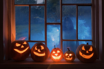 Halloween pumpins on windowsill with ghost outside  window