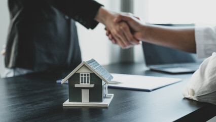 Home model. Real estate agents and buyers handshake after signing a business contract, renting, buying, mortgage, loan or home insurance