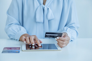 Consumer woman hand holding a mock up credit card, ready to spending pay online finance shopping according to discount products via Tablet from home office