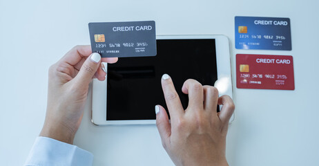 Consumer woman hand holding a mock up credit card, ready to spending pay online finance shopping according to discount products via Tablet from home office