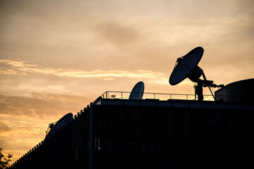 Yellow sunset with multiple satellite dishes antenna on the rooftop of international tv station...