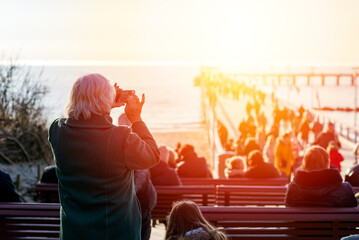 People admire the sunset on the sea pier. Palanga, Lithuania.Nice evening at sea.Rear view.