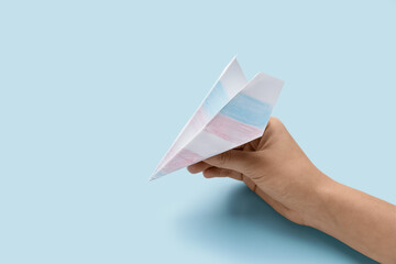 Hand with paper airplane on color background. Concept of transgender