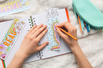Woman coloring bookmark on bed - obrazy, fototapety, plakaty