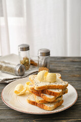 Plate with pieces of fresh bread and butter on table