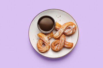 Plate with tasty churros and melted chocolate sauce on color background