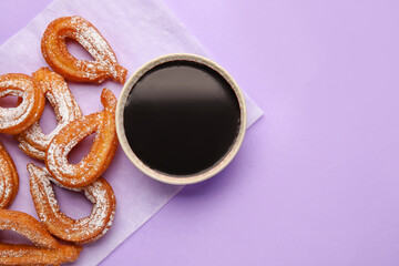 Parchment with tasty churros and melted chocolate sauce on color background, closeup