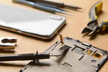 Disassembled mobile phone with technician tools on color background