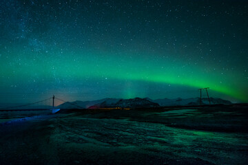 arctic landscape with a bridge and the beginning of a solar storm, aurora borealis