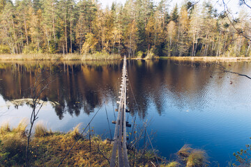 Narrow long wooden suspension bridge over the lake in Karelia, Russia. Beautiful autumn season landscape with river and forest stock photography