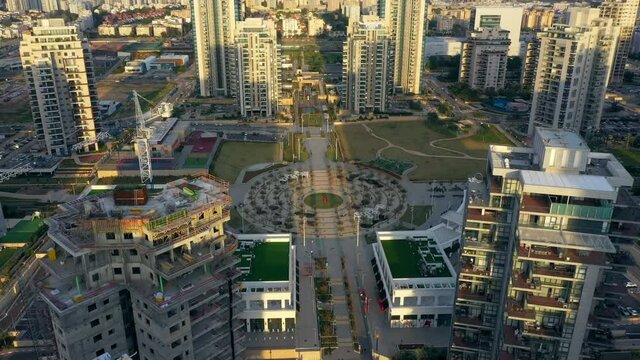 Aerial Tilt Down Shot Of Circular Park Amidst Buildings In City, Drone Flying Over People During Day - Netanya, Israel