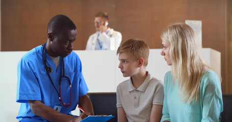 Afro-american pediatrician discussing test results with teen boy patient and worried mother