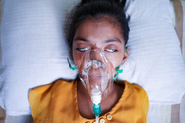 Close up top view of young kid breathing on ventilator oxygen mask due to coronavirus covid-19...