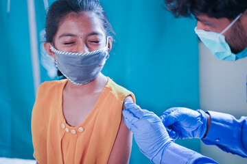 Concept of Covid-19 coronavirus vaccination for children - Young girl kid getting jab or vaccinated to against covid at hospital - obrazy, fototapety, plakaty