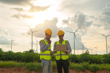 Teamwork of Asian windmill engineer group, worker working, using a computer laptop on site at wind...